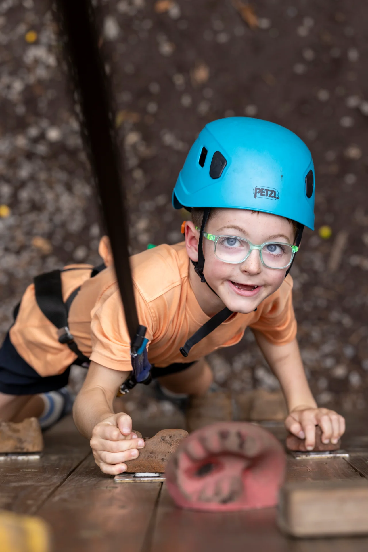 Massanutten kids adventure course smiling boy blue helmet climbing wall overhead