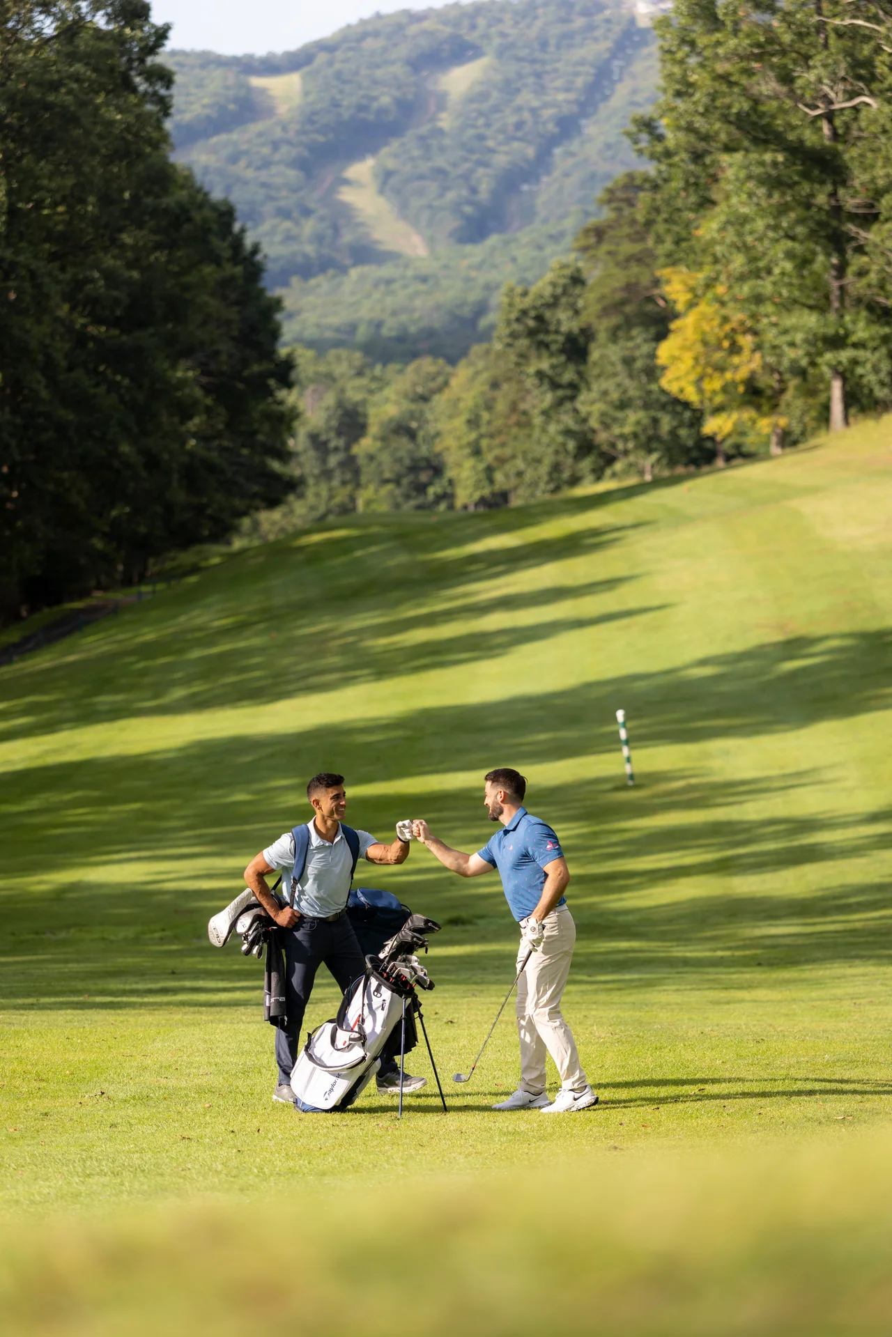 Massanutten mountain greens golfers fist bump beside bags fairway